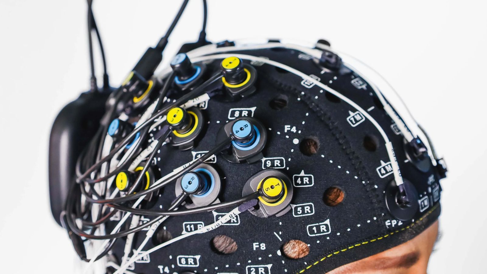 Czepek pomiarowy na głowie, z optodami fNIRS i elektrodami EEG rozmieszczonymi według siatki pozycji 10-20